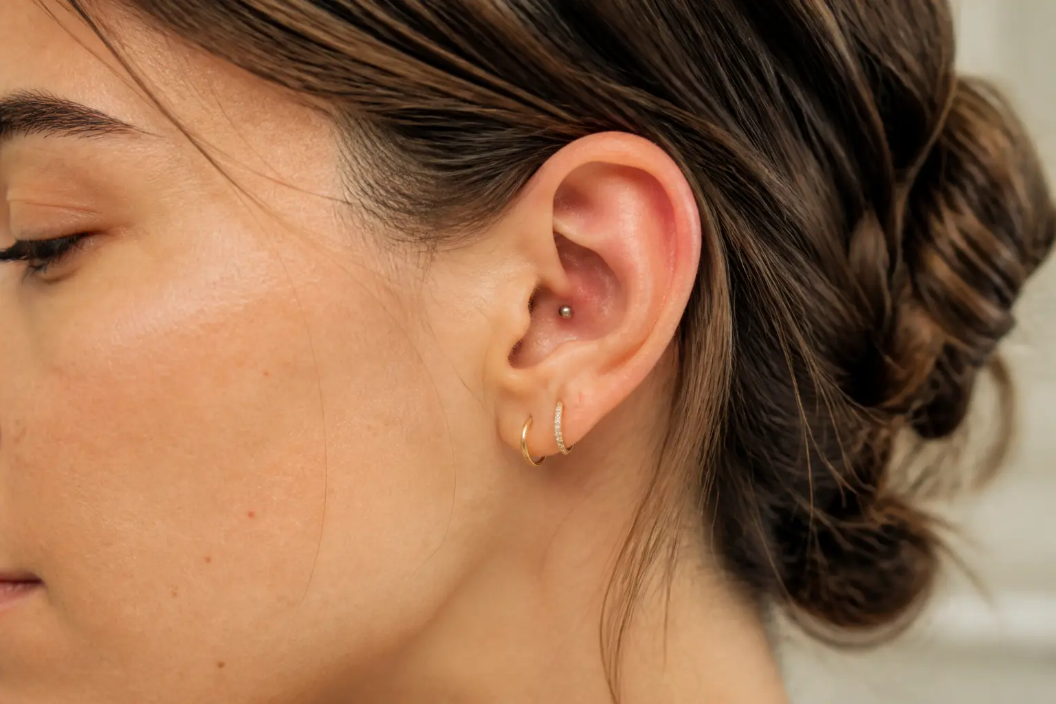 Piercing conch discret sur une oreille en gros plan, style éditorial naturel, lumière douce et fond flou