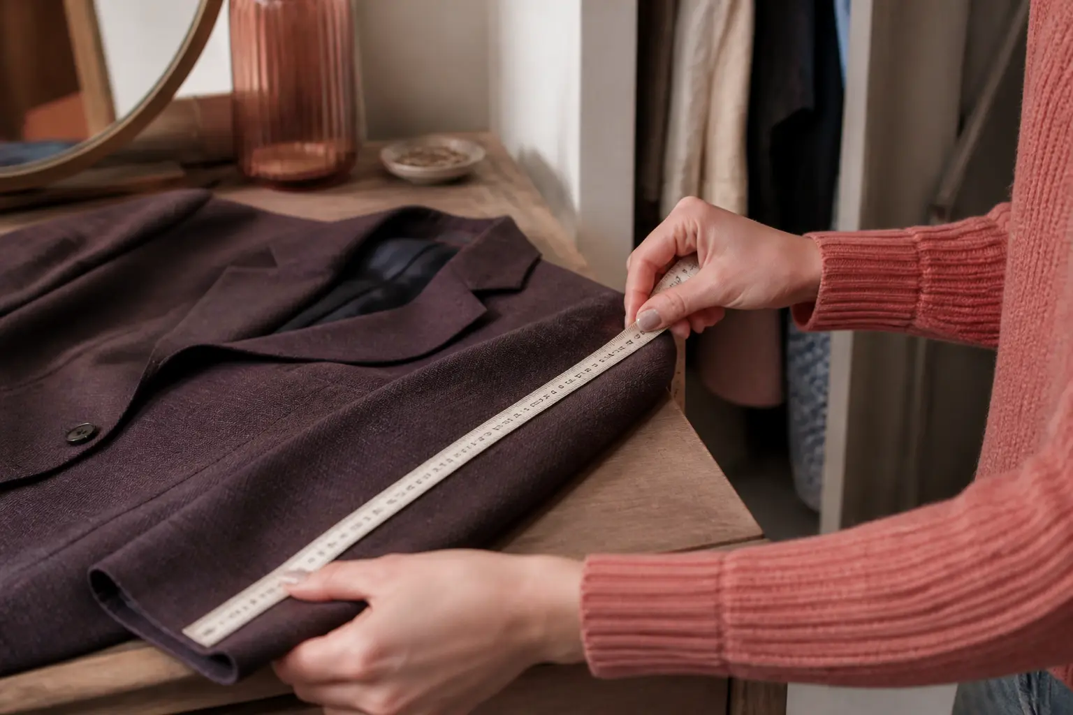 Correspondance taille : mètre ruban sur la manche d’une veste, près d’une coiffeuse et d’une armoire ouverte.