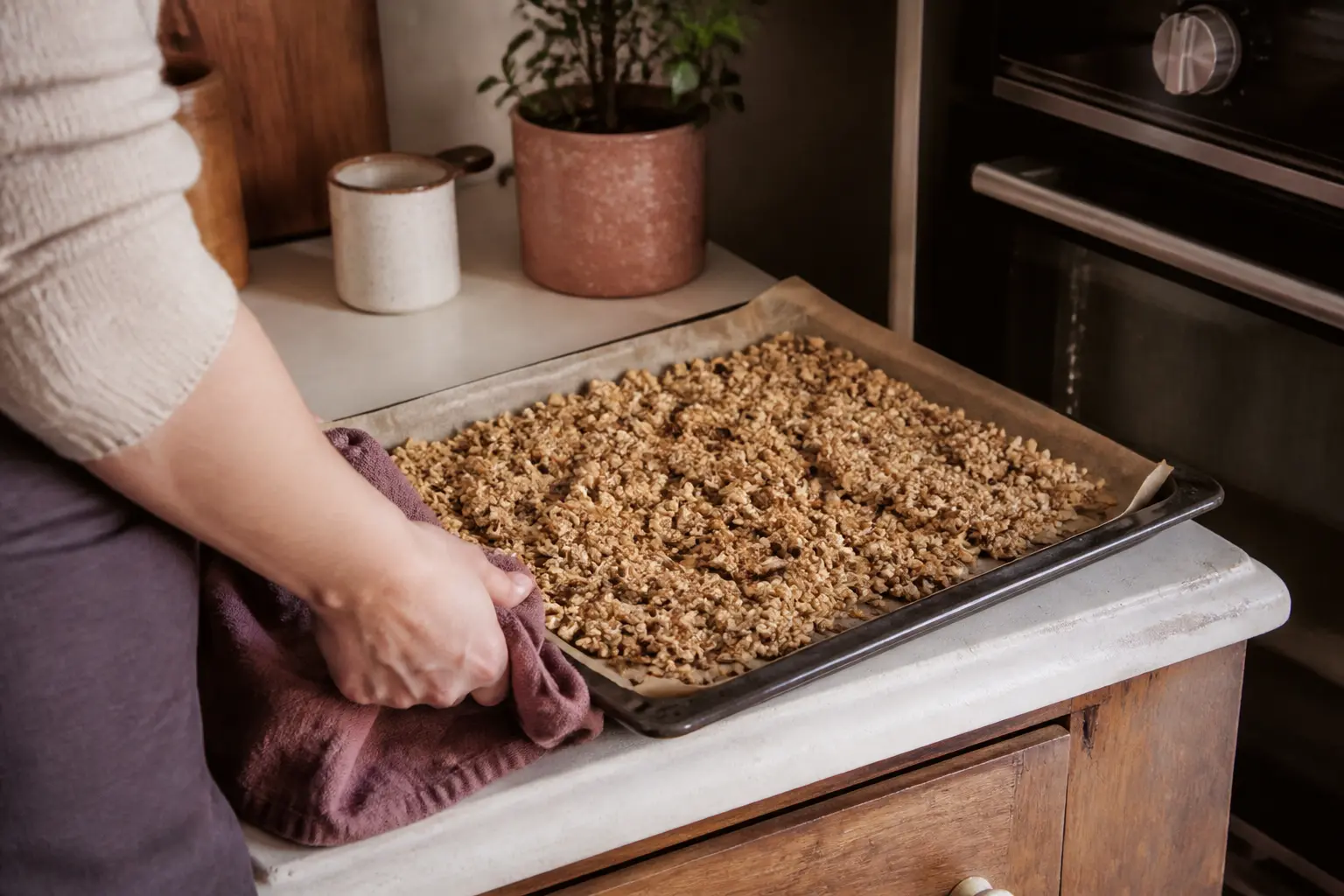 Granola maison en clusters sur une plaque, sur un plan de travail de cuisine chaleureux près du four, lumière douce naturelle