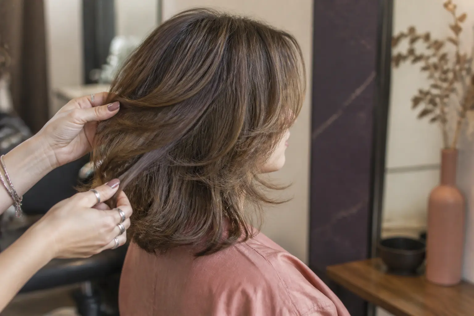 Coupe de cheveux mi long dégradé sur cliente en salon, couches souples et mouvement naturel autour du visage et des épaules