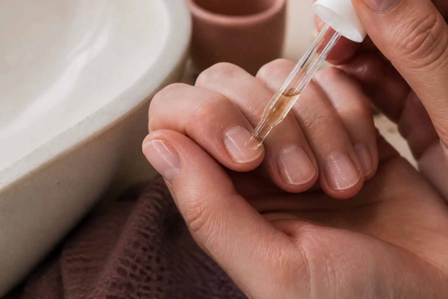 Huile de ricin et ongle : gros plan d’ongles secs enduits d’huile, près d’un lavabo, lumière douce naturelle